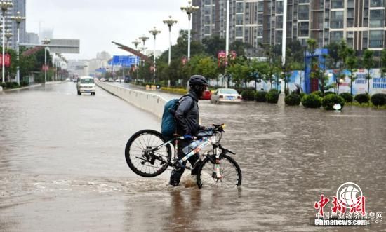 7月22日，民眾抬著自行車從積水路上走過。當(dāng)日，昆明持續(xù)降雨，城區(qū)多處路段積水。昆明市氣象臺發(fā)布暴雨藍(lán)色預(yù)警，未來12小時昆明市區(qū)及周邊多地區(qū)將持續(xù)降雨。 <a target=