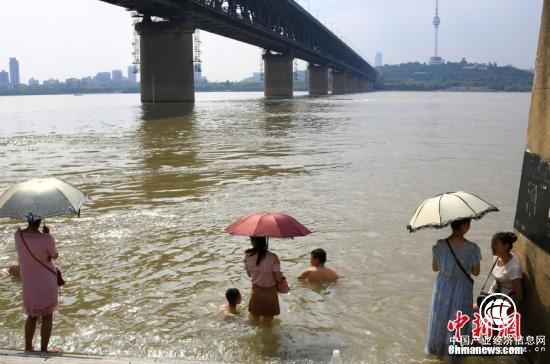 7月25日，武漢武昌江邊，市民打傘遮陽(yáng)站在水中降溫。。 <a target=